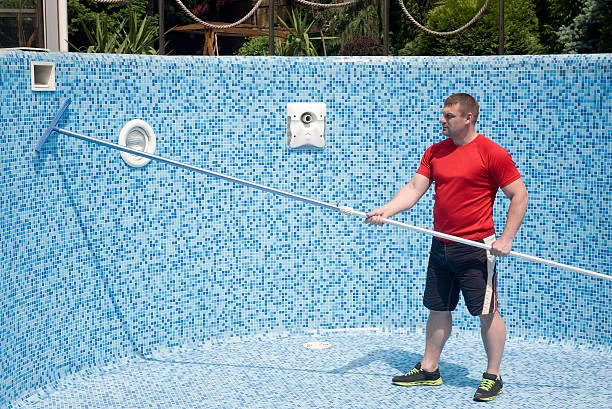 A man brushing the wall of pool